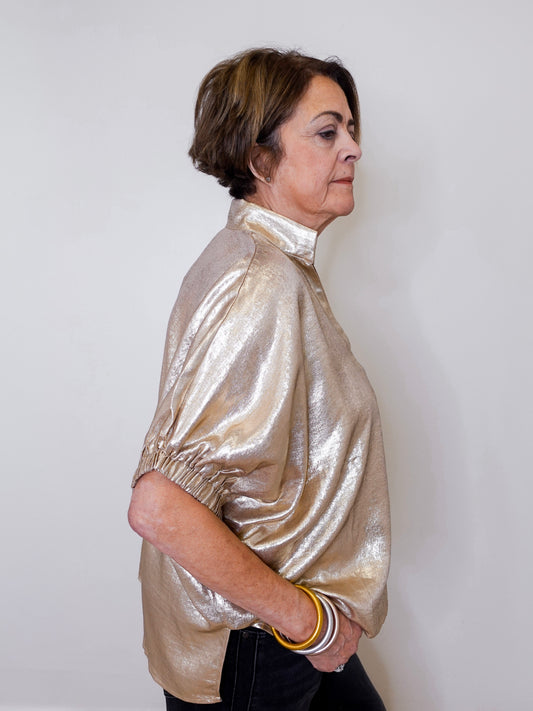 Woman wearing a shiny gold jacket against a white background