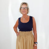 Woman wearing a navy top and beige skirt against a white background