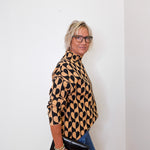 A woman modeling a mock neck heart pattern sweater in front of a white wall. 