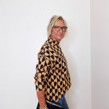 A woman modeling a mock neck heart pattern sweater in front of a white wall. 