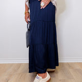 Person wearing a navy tiered skirt with white sneakers against a plain background