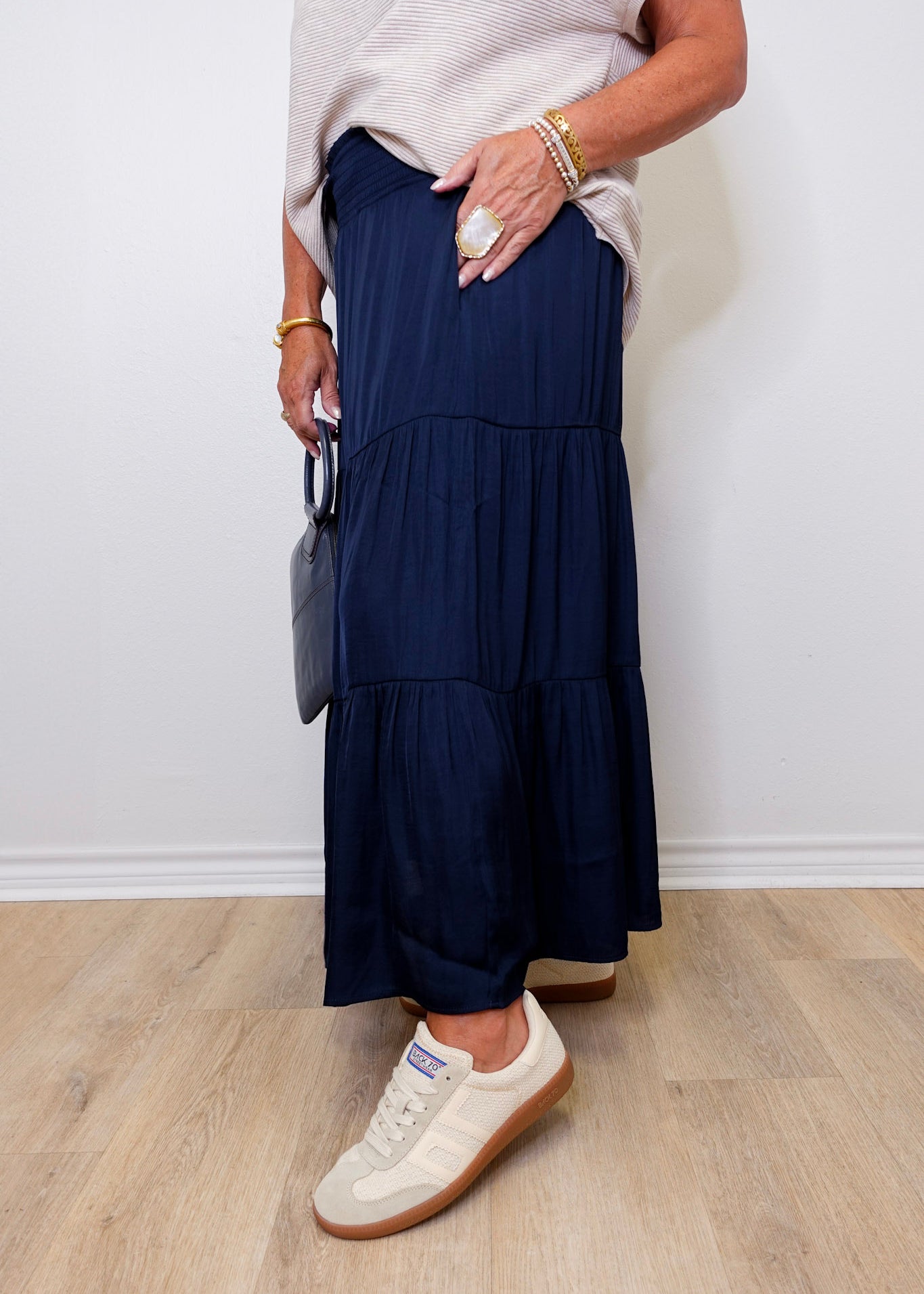 Person wearing a navy tiered skirt with white sneakers against a plain background