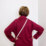 Person wearing a burgundy tracksuit against a white background
