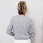 Person wearing a gray sweater with white polka dots against a white background