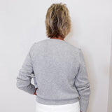 Person wearing a gray sweater with white polka dots against a white background