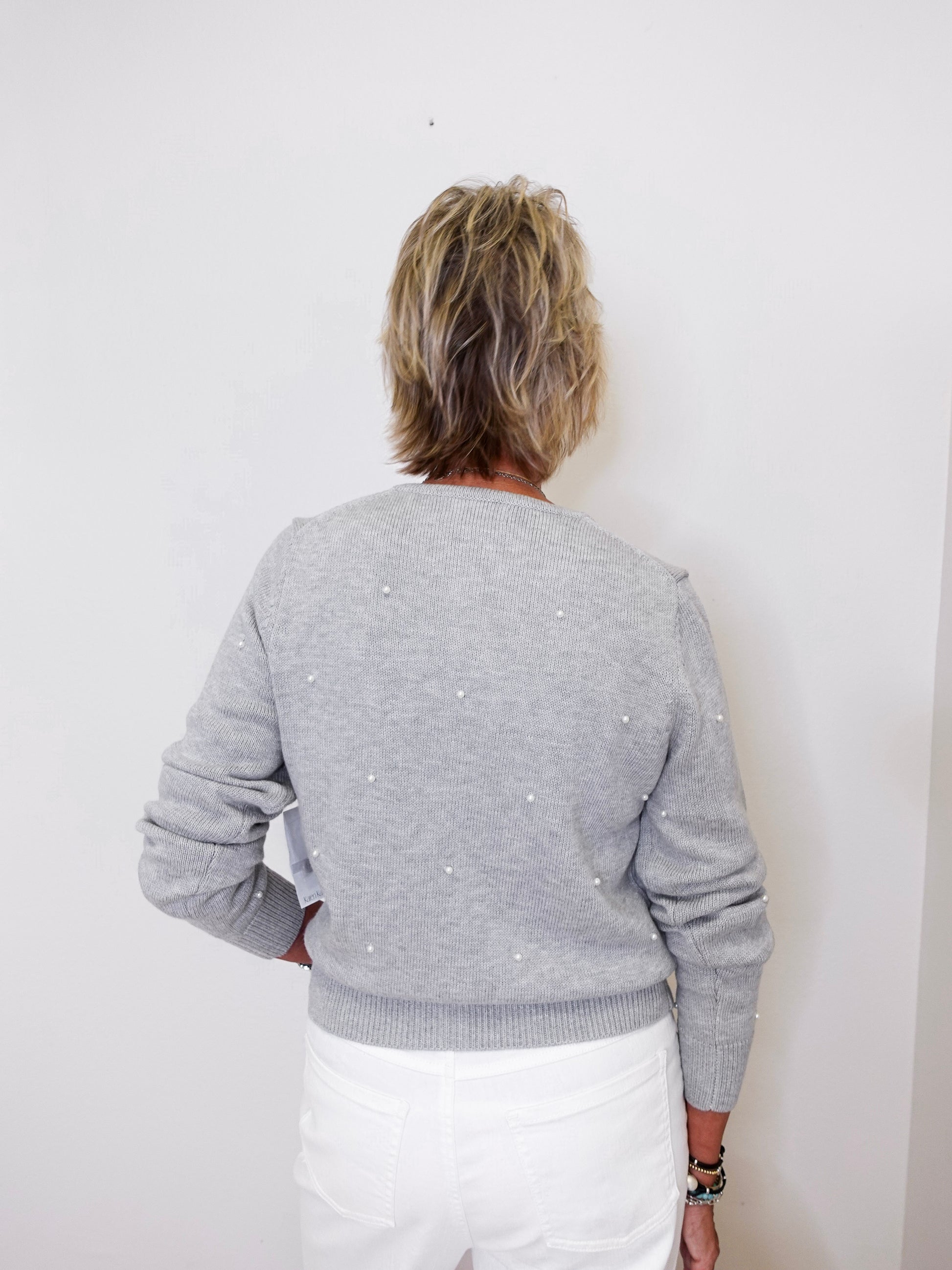 Person wearing a gray sweater with white polka dots against a white background