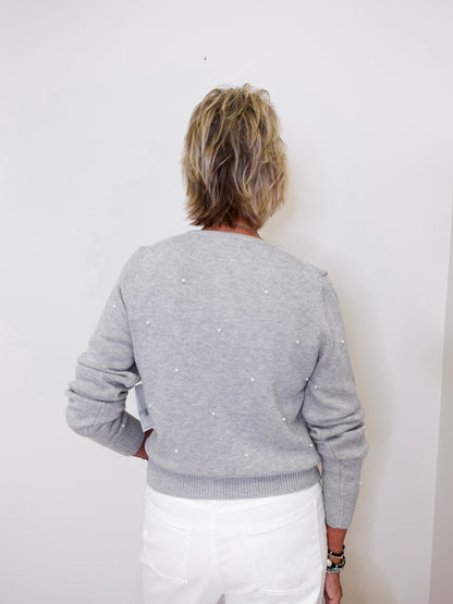 Person wearing a gray sweater with white polka dots against a white background