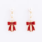pearl drop earrings with a red bow against a white background. 