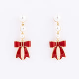 pearl drop earrings with a red bow against a white background. 