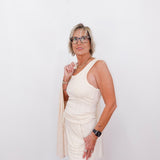Woman wearing a white sleeveless top and shorts with a beige cardigan against a white background