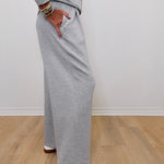 Person wearing gray sweatpants standing on a wooden floor with a white wall background