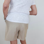 Person wearing a white t-shirt and beige shorts against a plain background