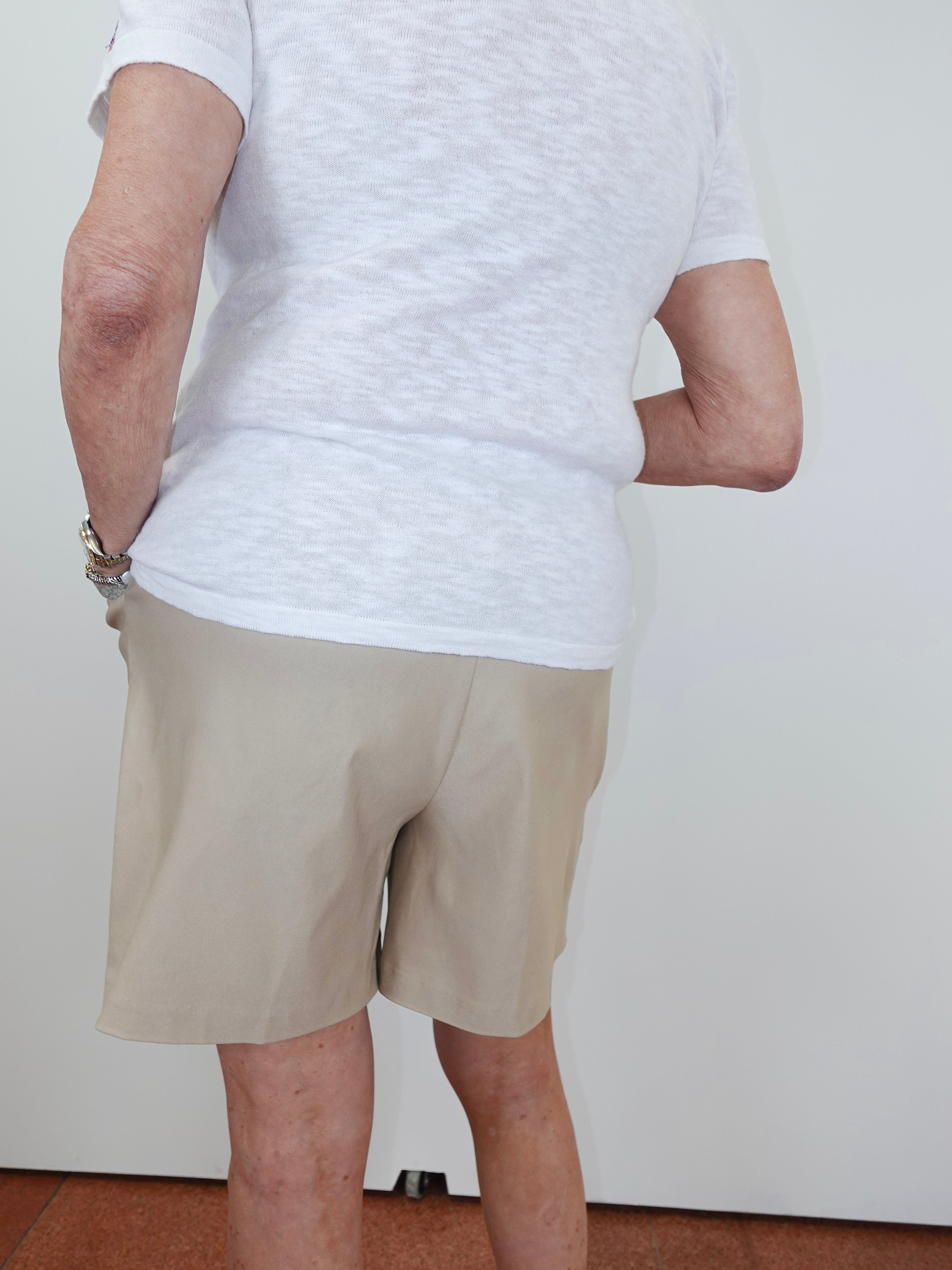 Person wearing a white t-shirt and beige shorts against a plain background