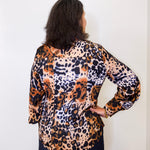 Person wearing a leopard print top against a white background