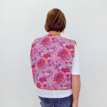 Person wearing a colorful floral-patterned vest on a white background