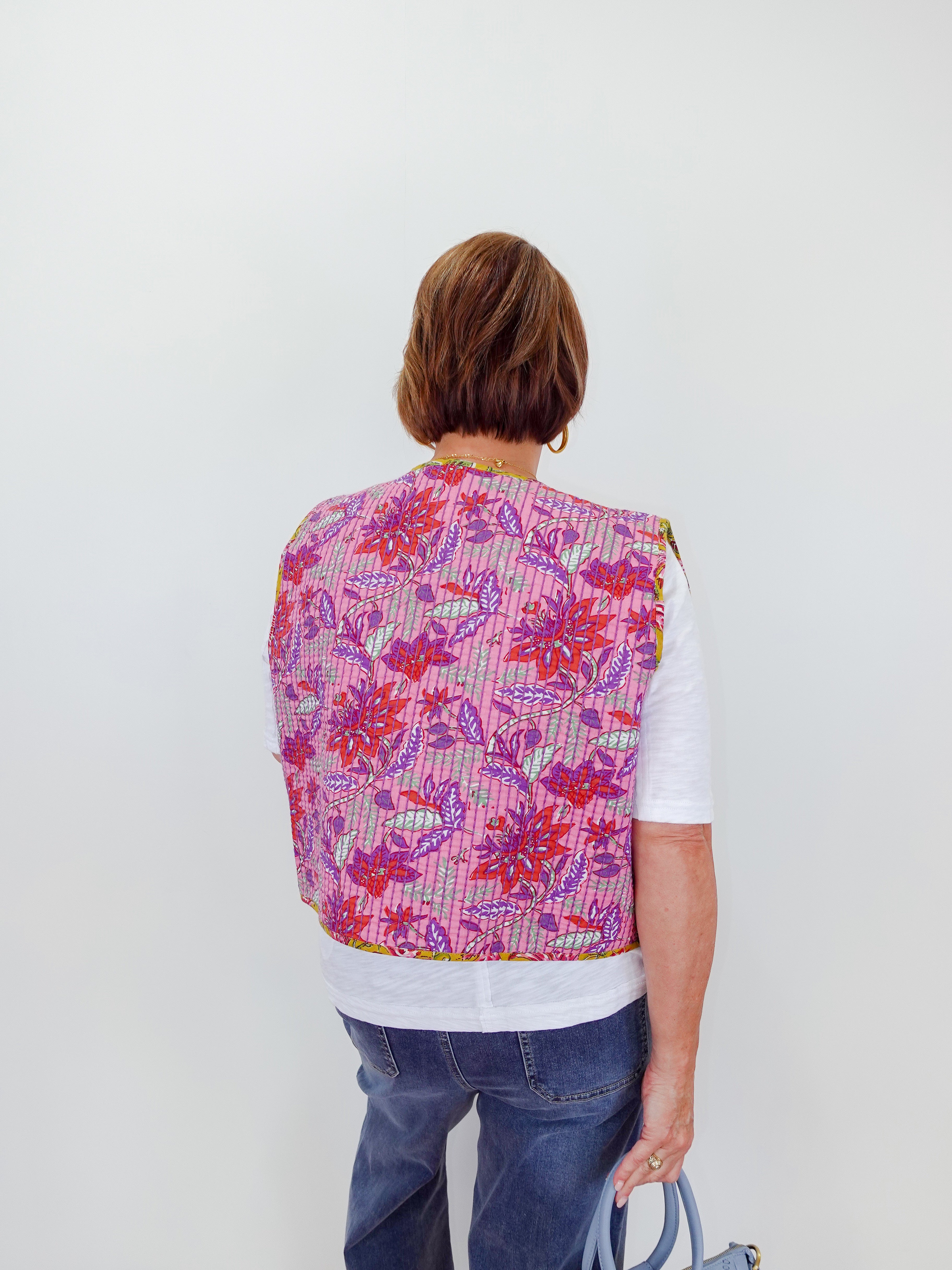 Person wearing a colorful floral-patterned vest on a white background