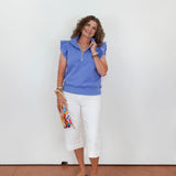Woman wearing a blue top and white pants against a plain background