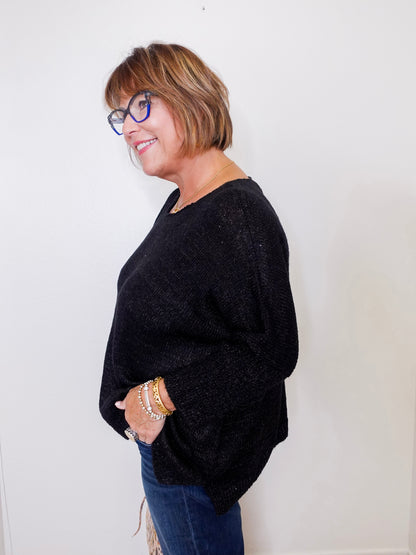 Woman wearing a black sweater and blue jeans against a white background