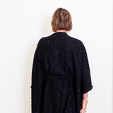 Person wearing a black textured cardigan against a white background