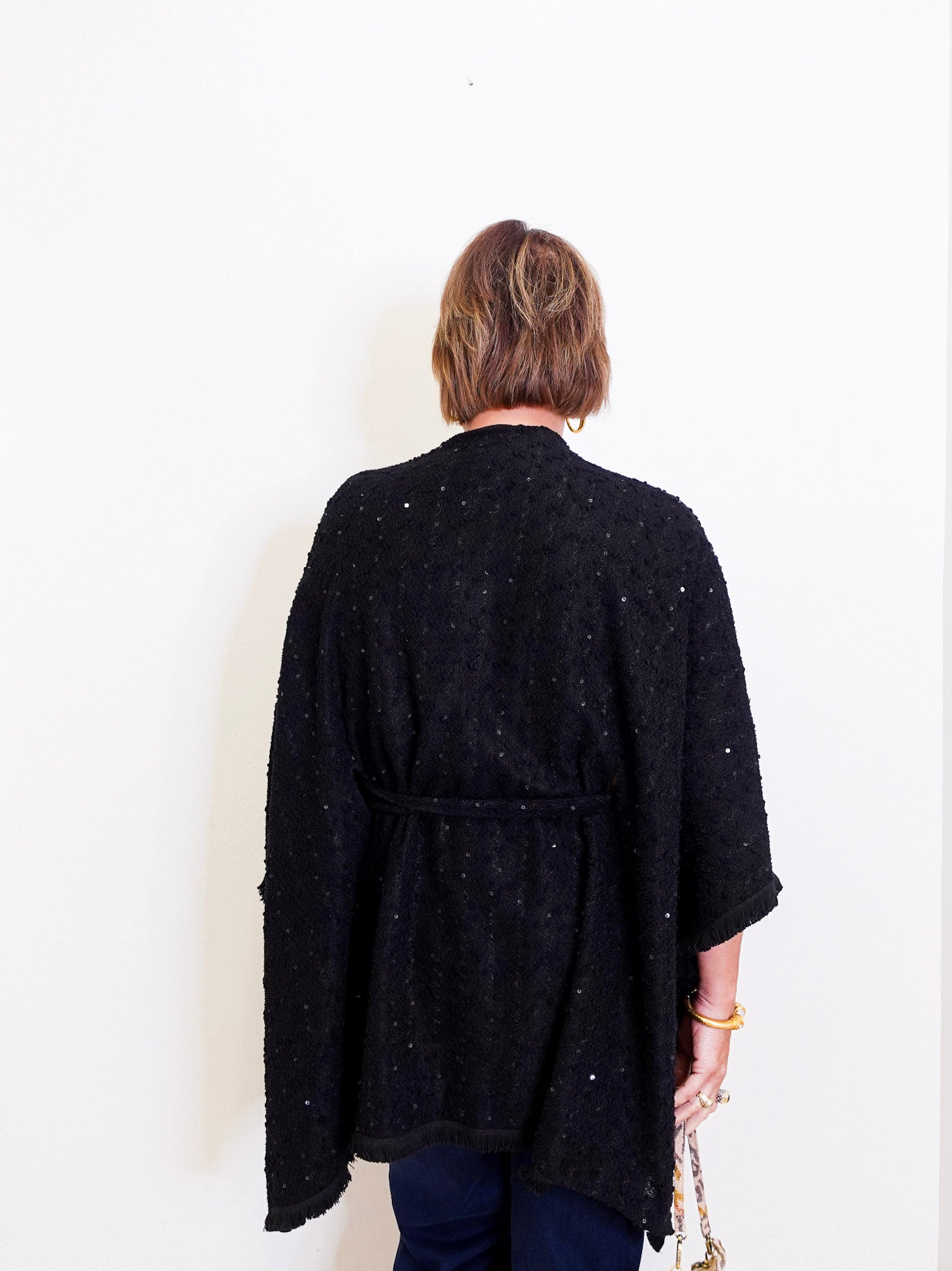 Person wearing a black textured cardigan against a white background