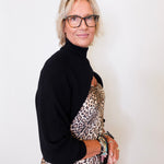 Woman wearing a black turtleneck and leopard print dress against a white background