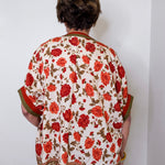 women wearing a floral print blouse against a white wall.