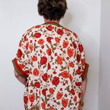women wearing a floral print blouse against a white wall.