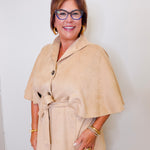 Woman wearing a beige cape top  over a white background