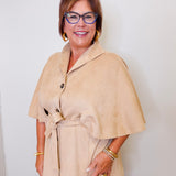 Woman wearing a beige cape top  over a white background