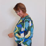Woman wearing a colorful patterned sweater against a white wall
