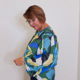 Woman wearing a colorful patterned sweater against a white wall
