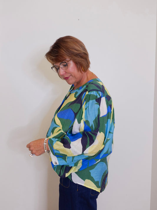 Woman wearing a colorful patterned sweater against a white wall