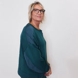 Person wearing a green sweater and glasses against a white background