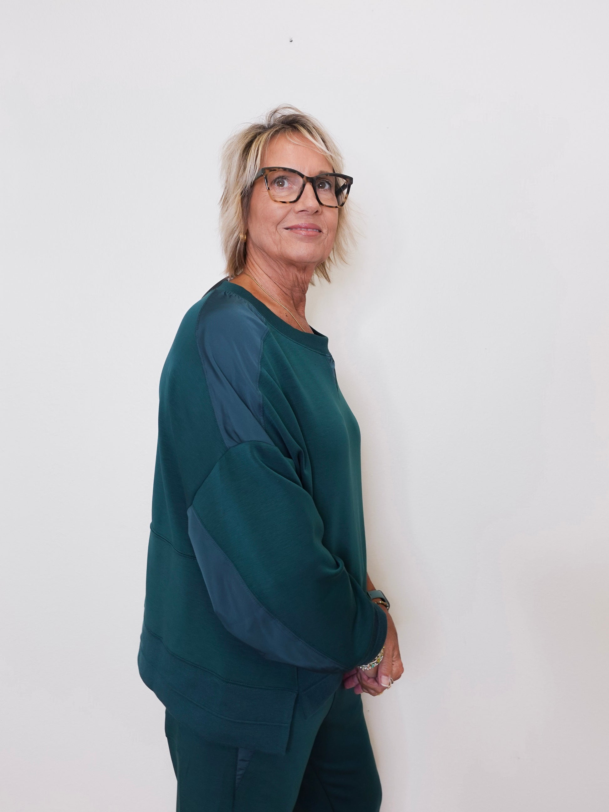 Person wearing a green sweater and glasses against a white background