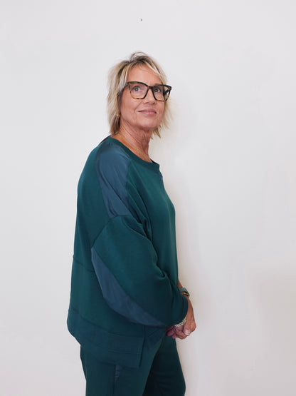 Person wearing a green sweater and glasses against a white background