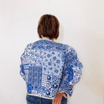 Person wearing a blue and white patterned shirt against a white background