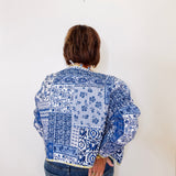 Person wearing a blue and white patterned shirt against a white background