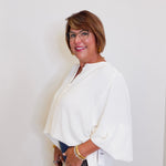 Woman wearing a white blouse and glasses against a plain background