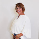 Woman wearing a white blouse and glasses against a plain background