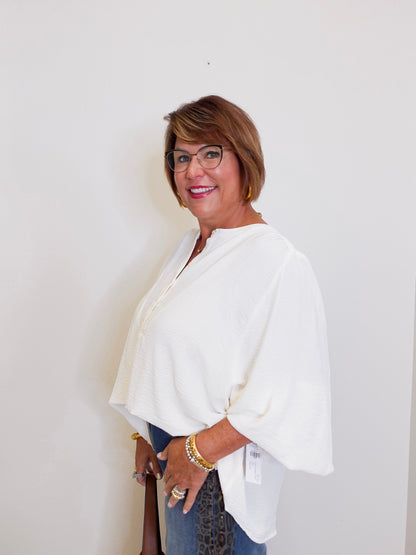 Woman wearing a white blouse and glasses against a plain background
