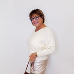 Woman wearing a white top and beige pants with a red handbag against a white background