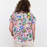 Person wearing a colorful floral shirt and beige shorts on a white background
