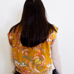 Person wearing a yellow floral vest against a white background