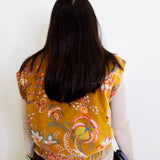 Person wearing a yellow floral vest against a white background