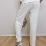 Person wearing white pants and transparent shoes on a wooden floor.