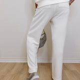 Person wearing white pants and transparent shoes on a wooden floor.