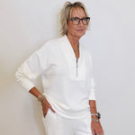 Woman in a white outfit posing against a plain background