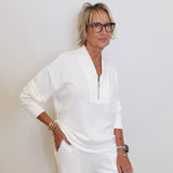 Woman in a white outfit posing against a plain background