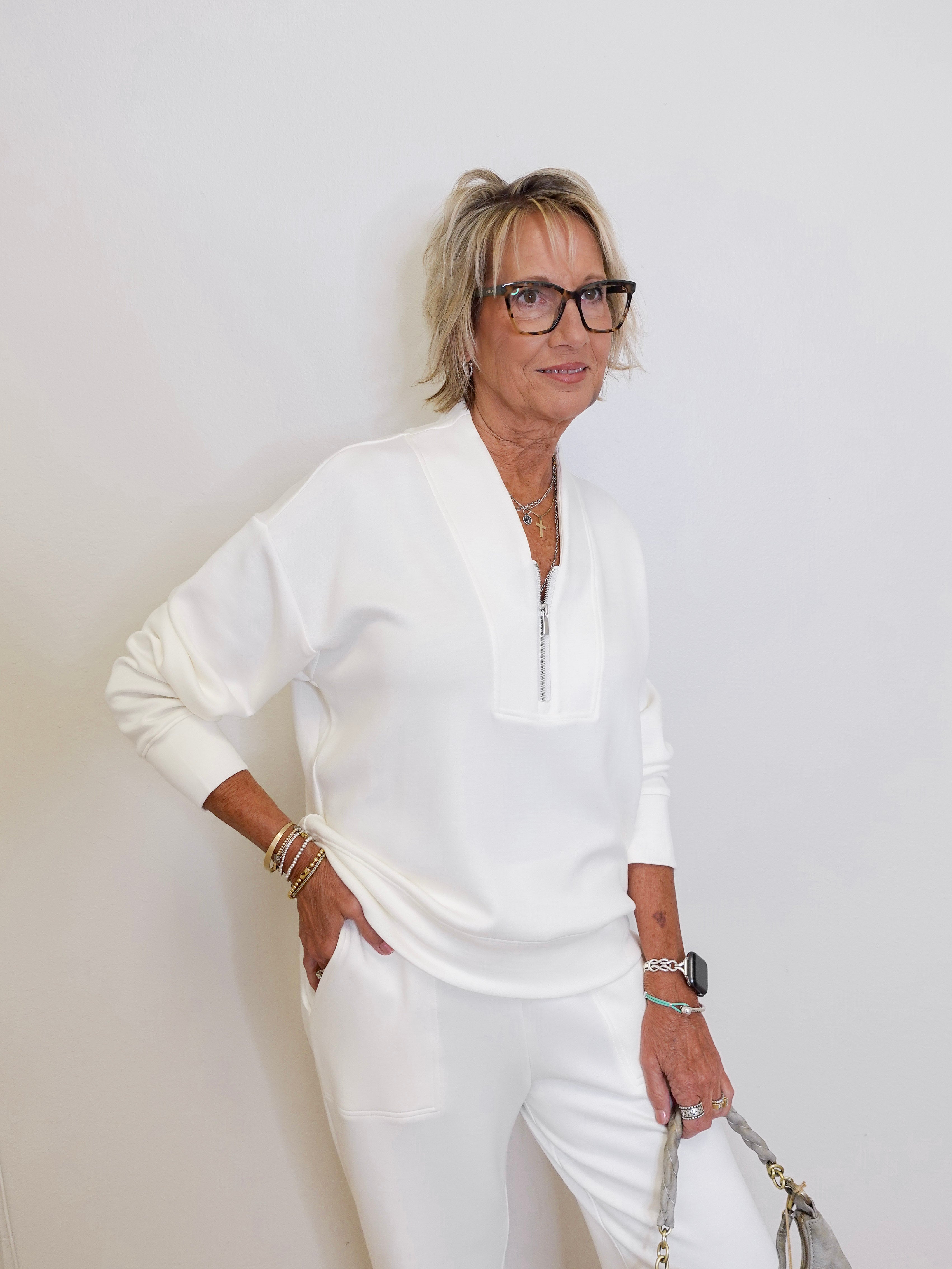 Woman in a white outfit posing against a plain background