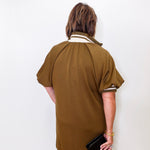Person wearing a brown dress with white trim against a white background